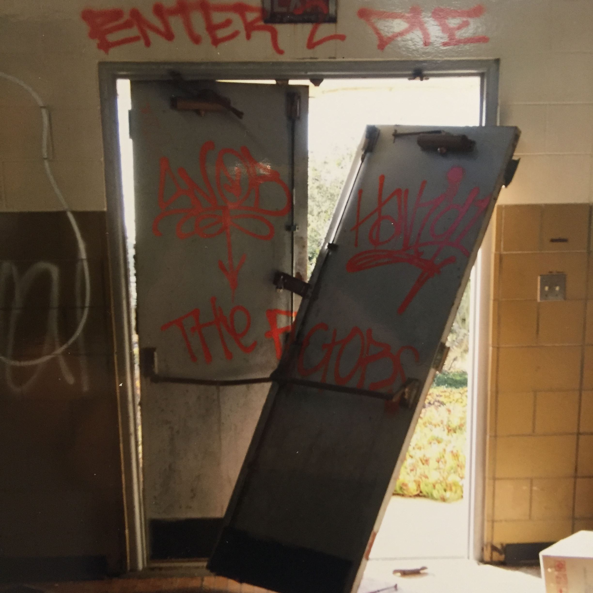 Photograph of graffiti on door with one door off the hinges 